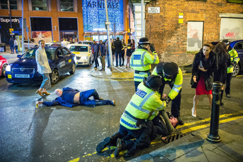 Joel Goodman's photo of police detaining a man while another lies collapsed in the road in Manchester, 1 January 2016
